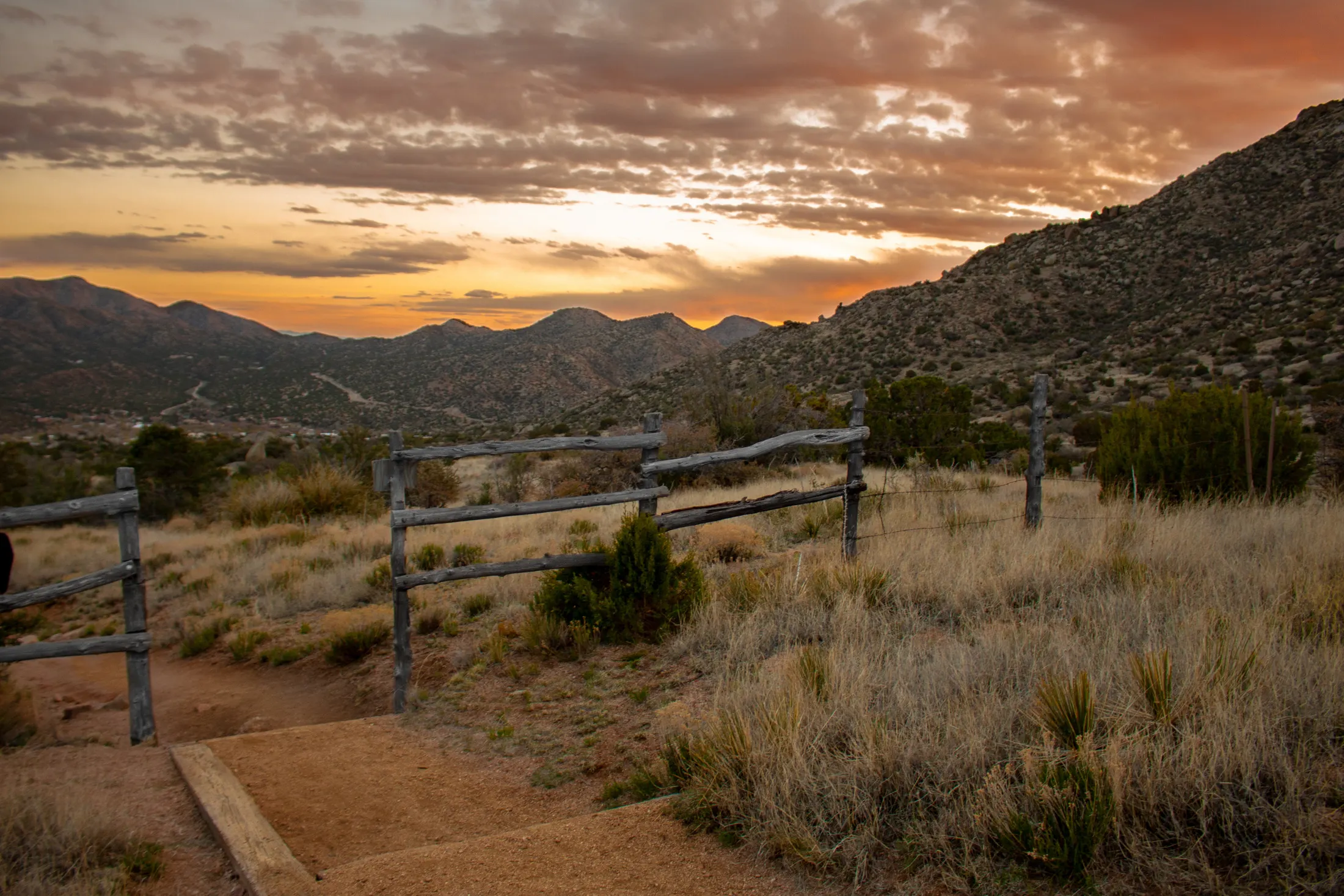 A rail-style fence line running across open high-desert scrubland under a wide sky