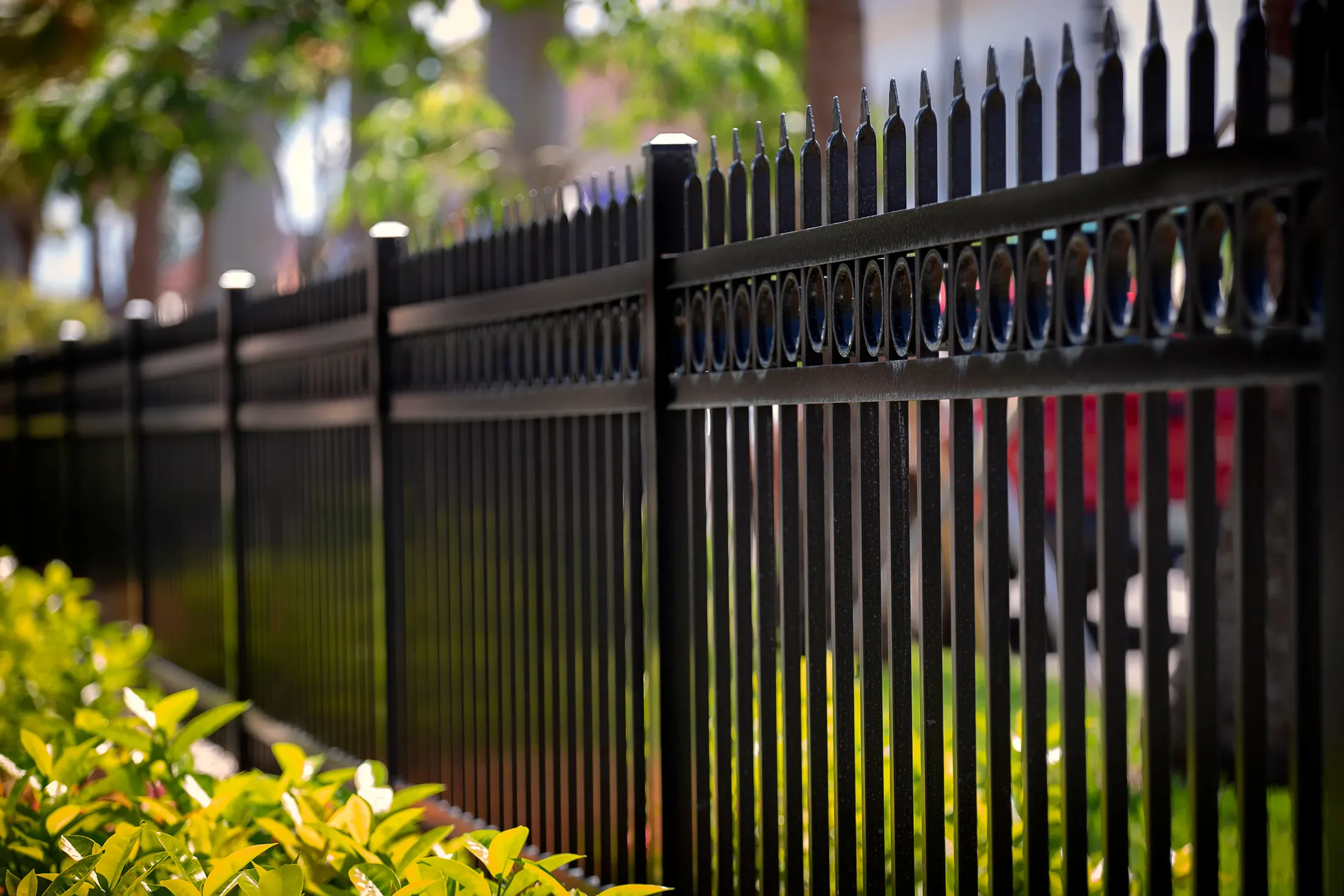 A black ornamental metal fence with vertical pickets along a residential property line